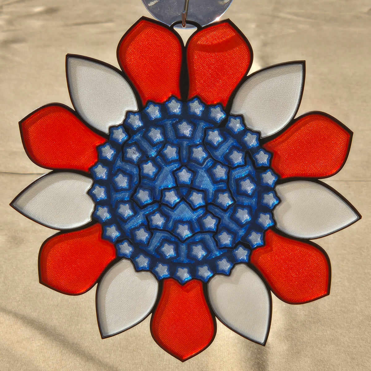 A circular decorative ornament or medallion with a red and white petal-like border surrounding a blue star-patterned center, shown against a light beige background.