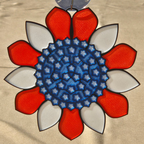 A circular decorative ornament or medallion with a red and white petal-like border surrounding a blue star-patterned center, shown against a light beige background.
