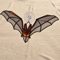 A 3D printed bat ornament with translucent gray wings, black outlines, and orange accents, attached to a clear suction cup against a beige fabric background.