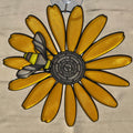 A 3D printed black eyed susan ornament with a bumblebee on one of its yellow petals, suspended by a clear plastic hook against a neutral background.