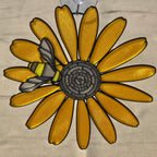 A 3D printed black eyed susan ornament with a bumblebee on one of its yellow petals, suspended by a clear plastic hook against a neutral background.