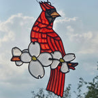 A 3D printed suncatcher depicting a cardinal perched on a flowering branch, suspended against a cloudy sky background.
