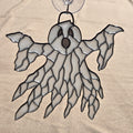 A ghost-shaped 3D printed ornament with a clear suction cup at the top, featuring a white and gray patterned body outlined in black, set against a beige fabric background.