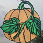 A 3D printed pumpkin ornament featuring a textured gold pumpkin body with a green stem, leaves, and a kissing couple's profile in the center, shown against an outdoor sky background.