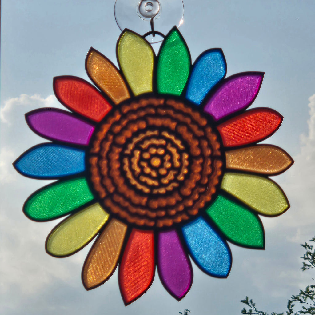 A 3D printed sunflower hanging in the sky, featuring a brown textured center and rainbow-colored petals outlined in black.