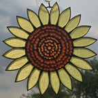 A 3D printed sunflower ornament hanging against an outdoor sky background, featuring textured pale yellow petals and a detailed brown glass center.